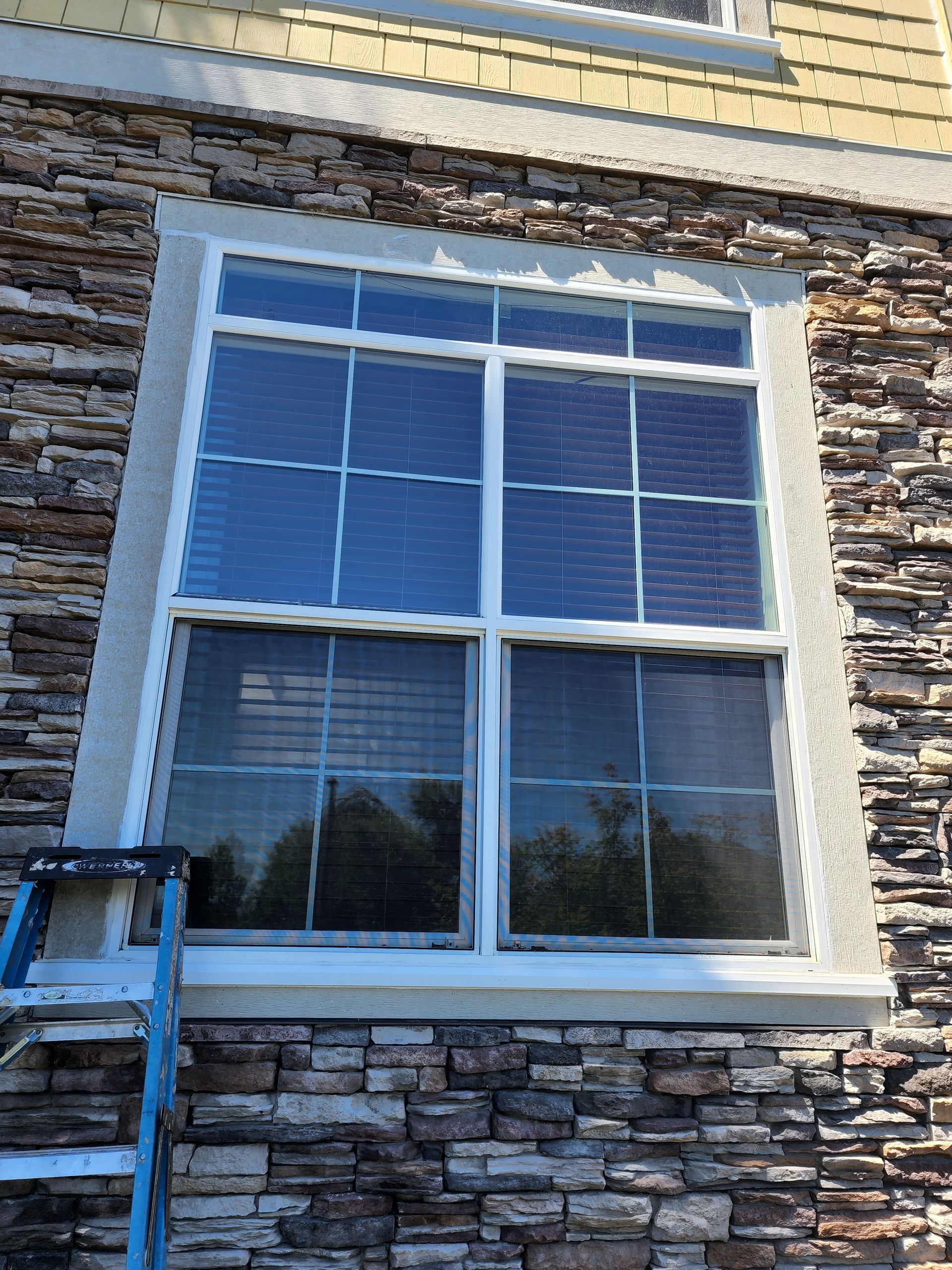 A window on the side of a building with a ladder in front of it.