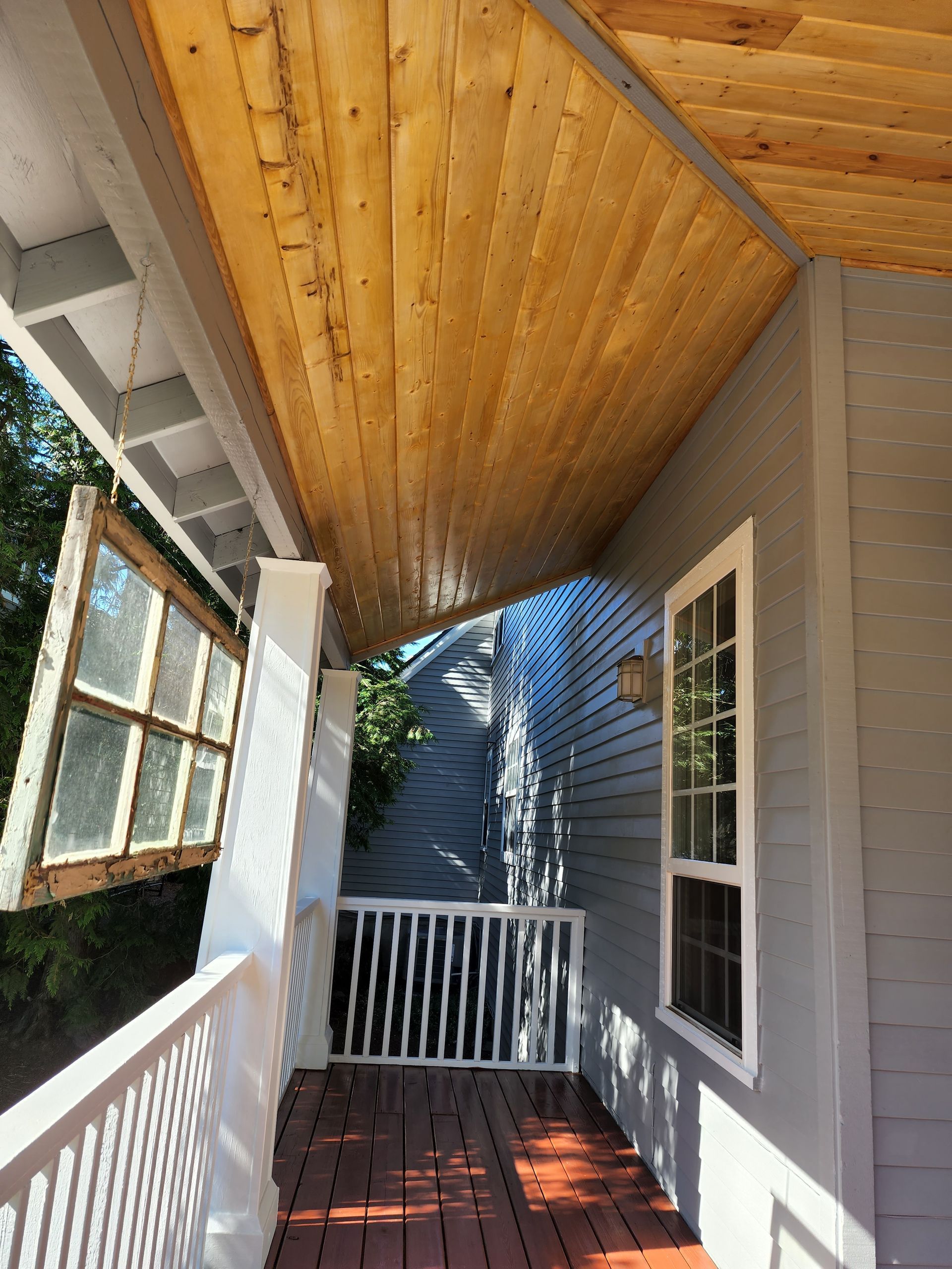 A porch with a wooden ceiling and a white railing