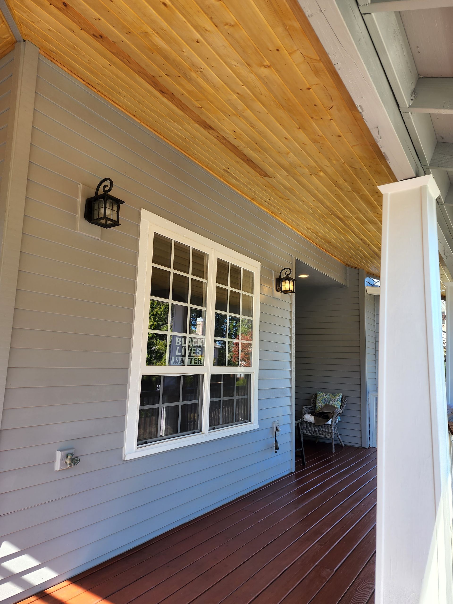 A porch with a wooden ceiling and a large window.