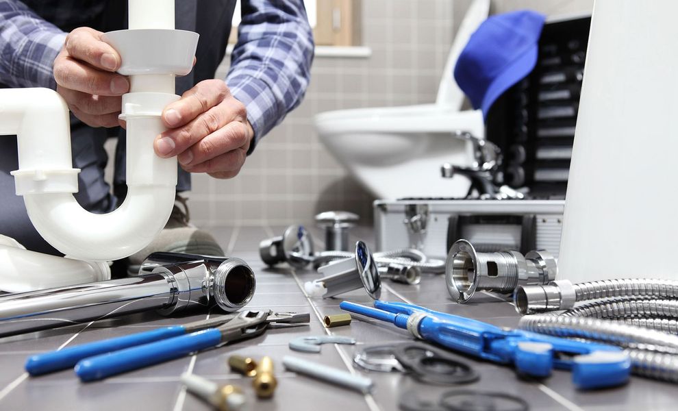 A plumber is fixing a sink in a bathroom.