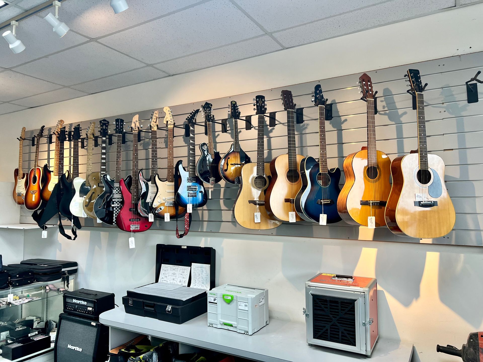 Many guitars are hanging on a wall in a store