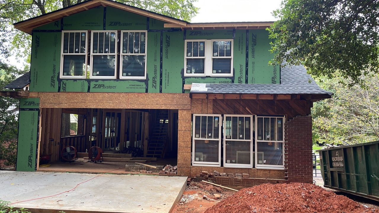 A house is being built with green siding and windows.
