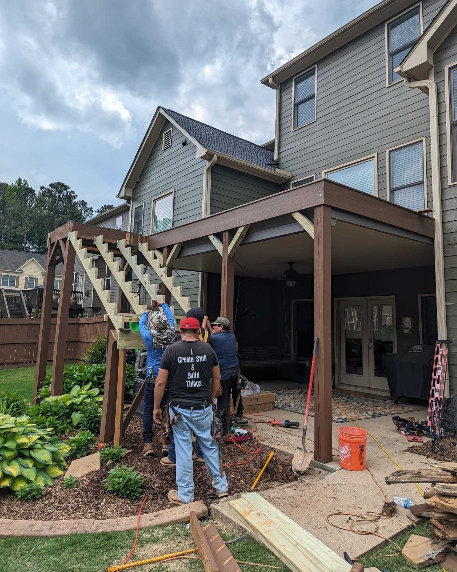 A group of men are working on a deck in front of a house.