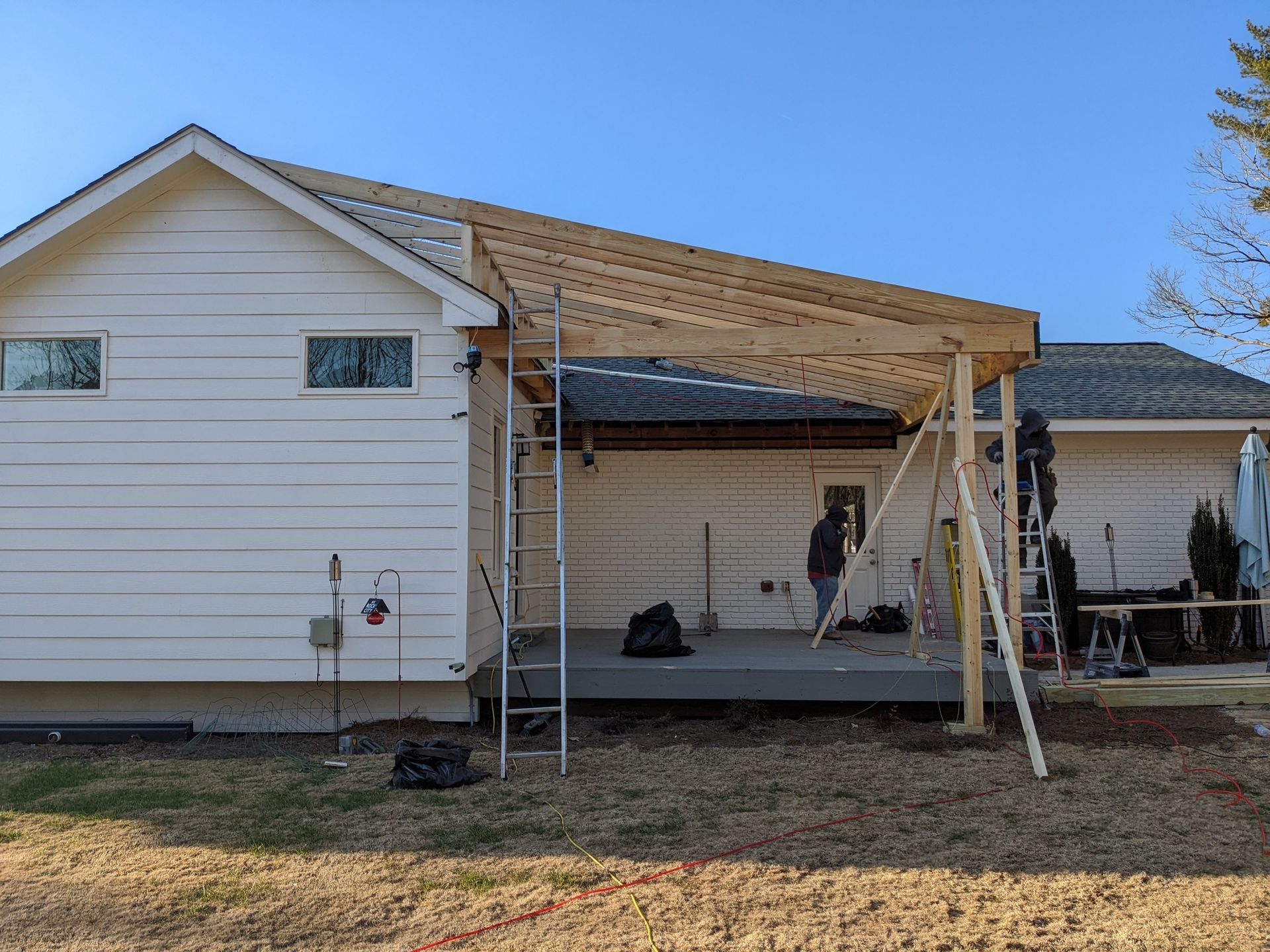 A man is standing on a ladder in front of a house under construction.