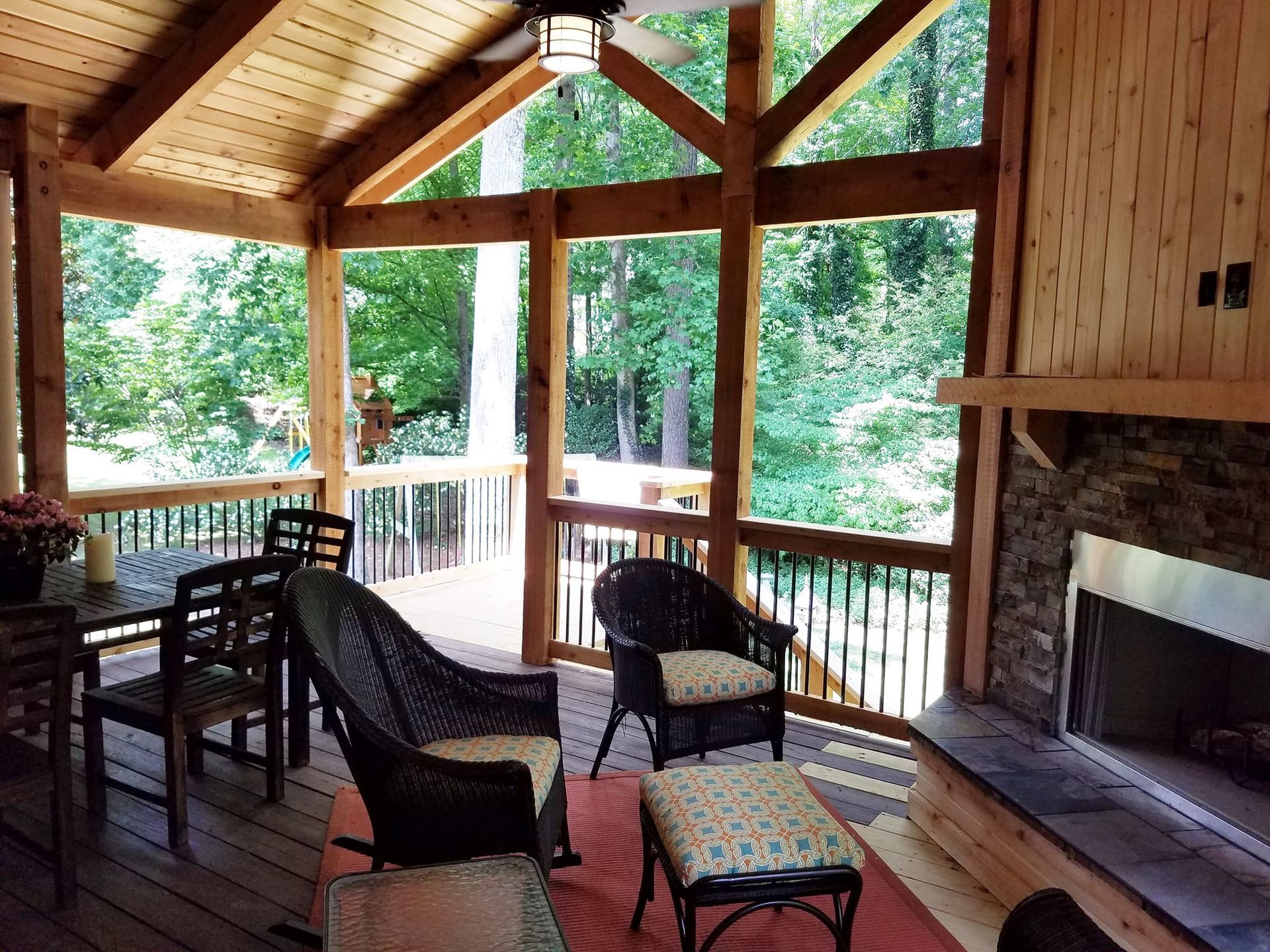 A screened in porch with a fireplace and chairs