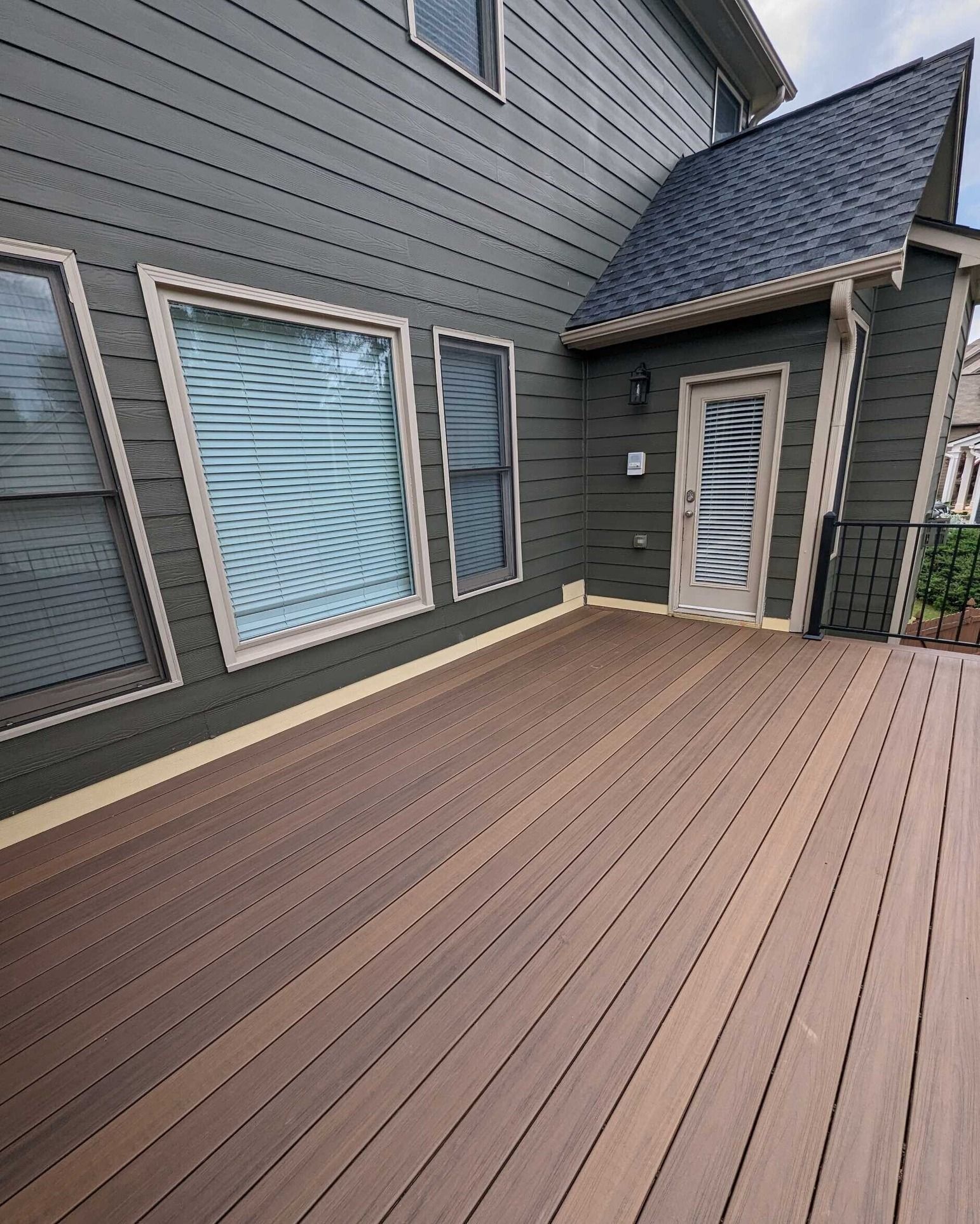 A large wooden deck is sitting in front of a house.
