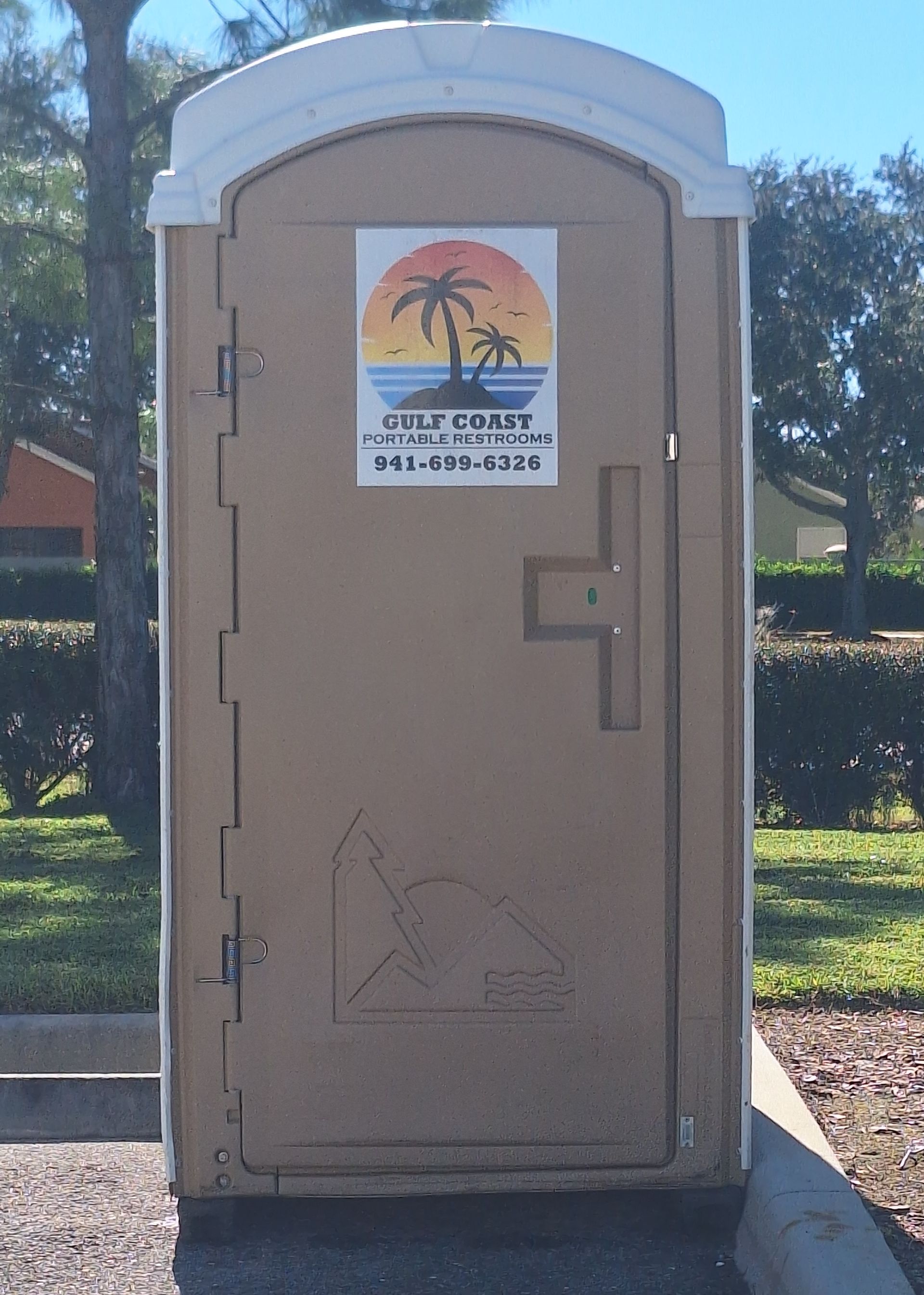 Portable beige restroom on a concrete pad, with a palm-tree sign and trees in the background.