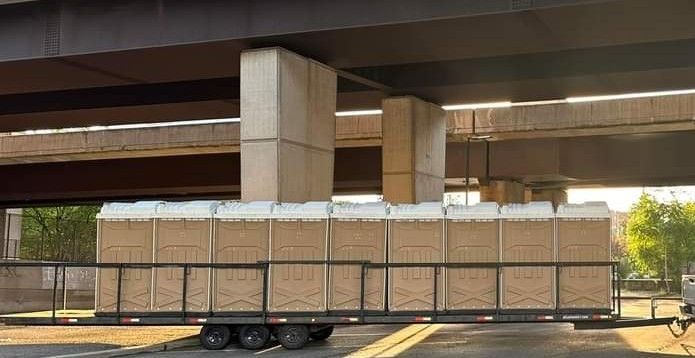 Trailer loaded with stacked cardboard boxes under an overpass in daylight