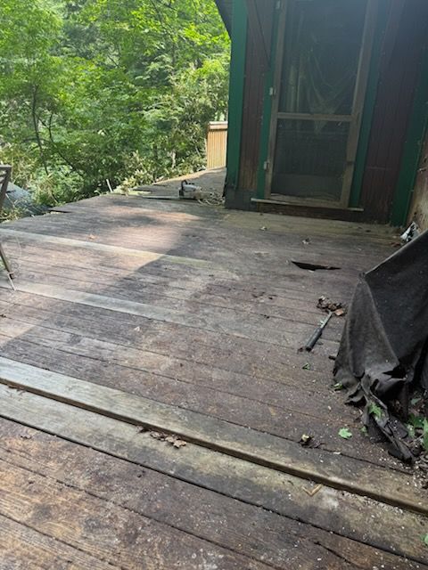 A wooden deck with a screen door and a hammer on it.
