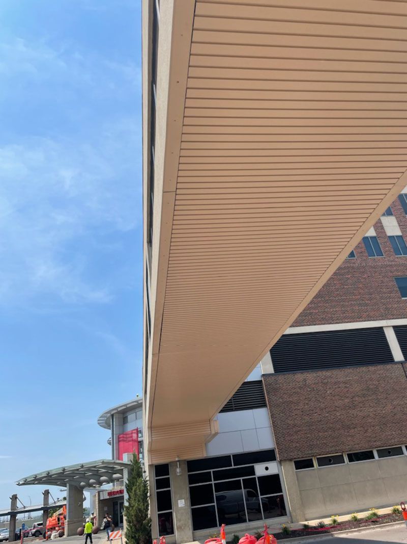 Overhead view of a beige bridge connecting to a brick building under a blue sky.
