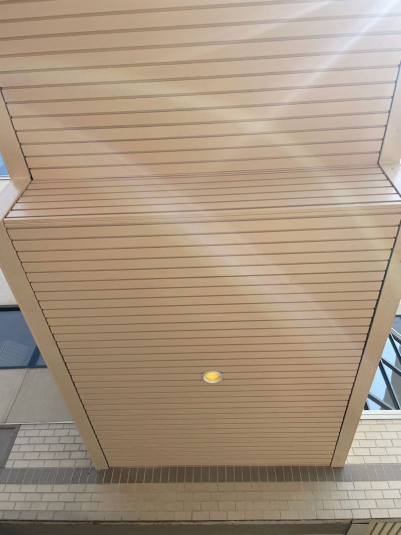 Beige wooden ceiling with recessed light, viewed from below.