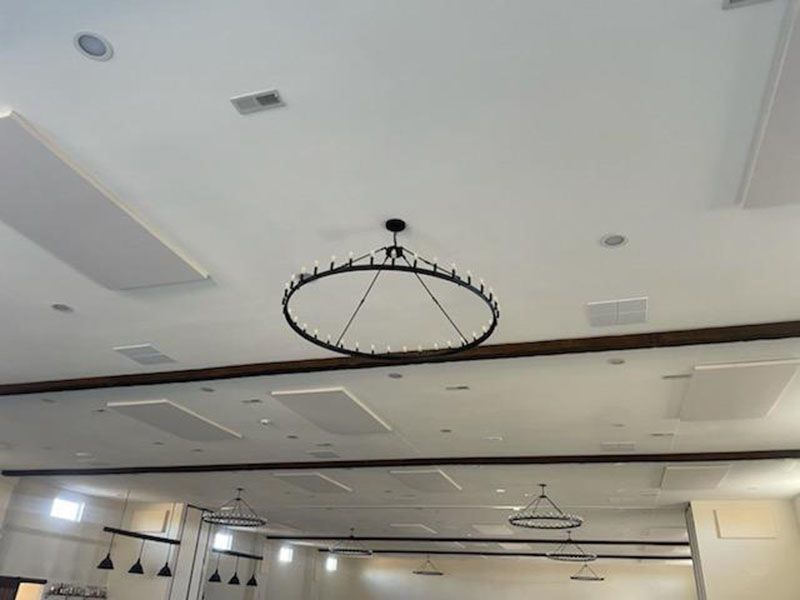 Large, round chandelier hanging from a white ceiling.  Recessed lights and other fixtures are also visible.