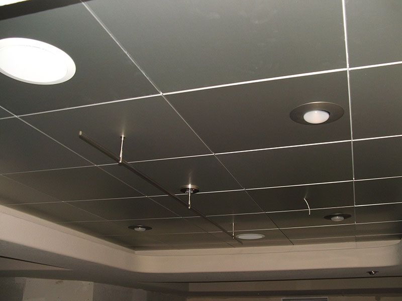 Silver ceiling tiles with recessed lighting, wires hanging down.