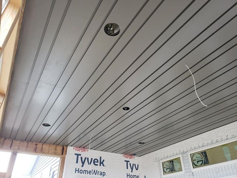 Gray, grooved ceiling with recessed lights; white Tyvek HomeWrap and window visible.