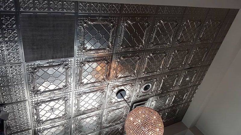 Silver, patterned ceiling tiles with a central light fixture and a decorative hanging light.