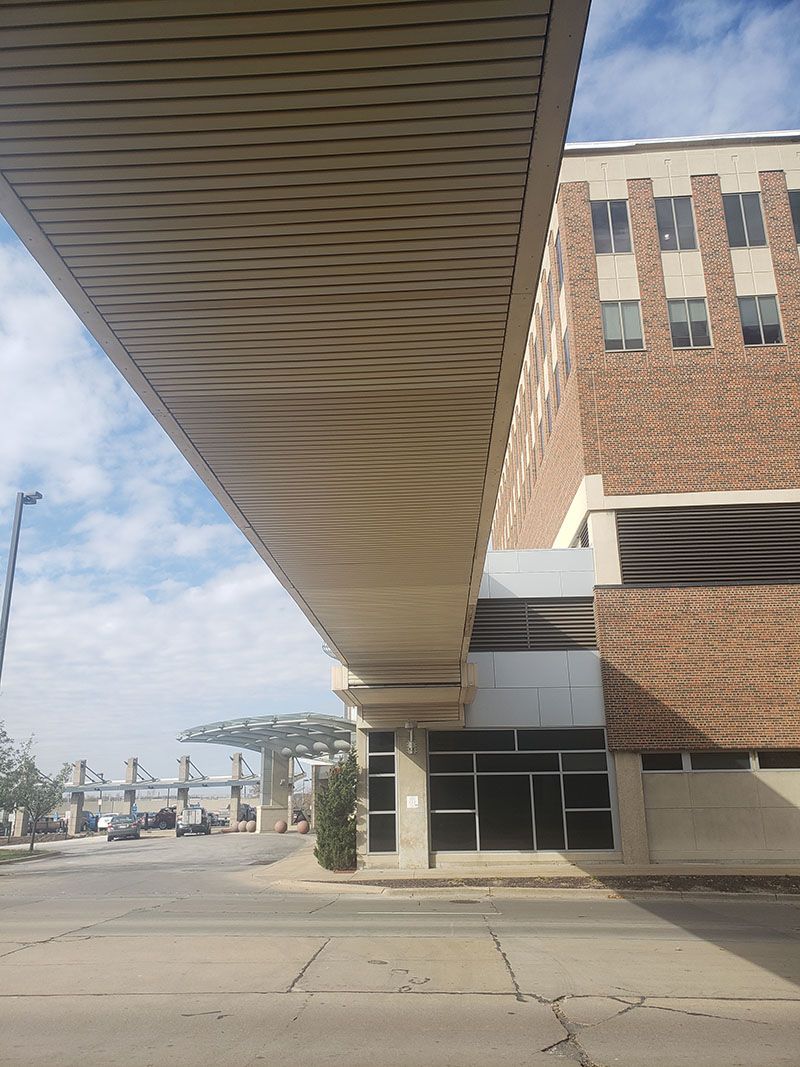Long elevated walkway connects to a brick building. Sky above, gray pavement below.