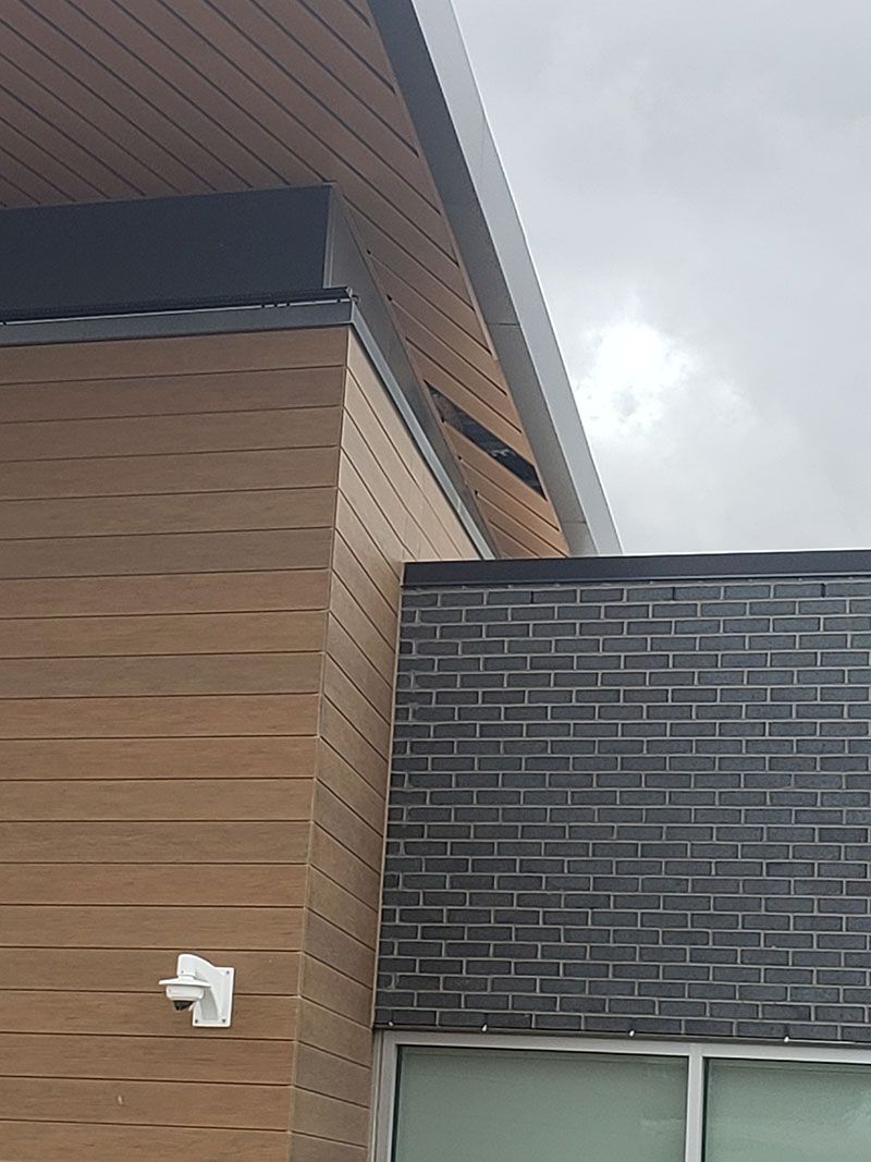Exterior of a building with wood siding and brick facade. Overcast sky.