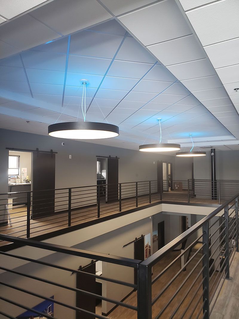 Multi-level office interior with overhead round lights, dark barn doors, and metal railings.