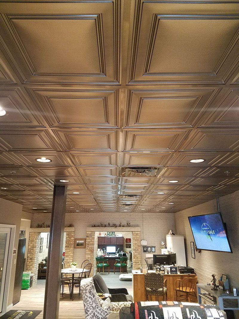 Metallic tile ceiling in a room with a TV, open doorway, and various furnishings.