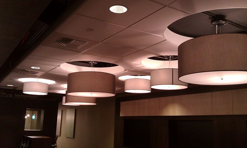 Overhead view of a ceiling with several pendant lights, each with a cylindrical shade.
