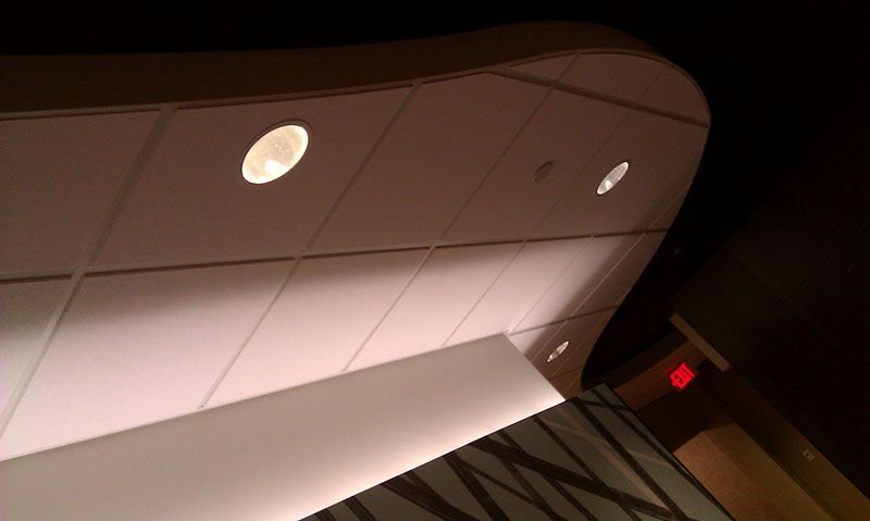 White curved ceiling with recessed lights, exit sign visible.