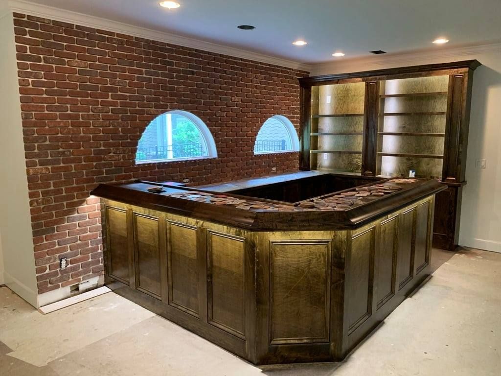 Empty brick-lined room with a large octagonal wooden bar or display counter and arched windows.