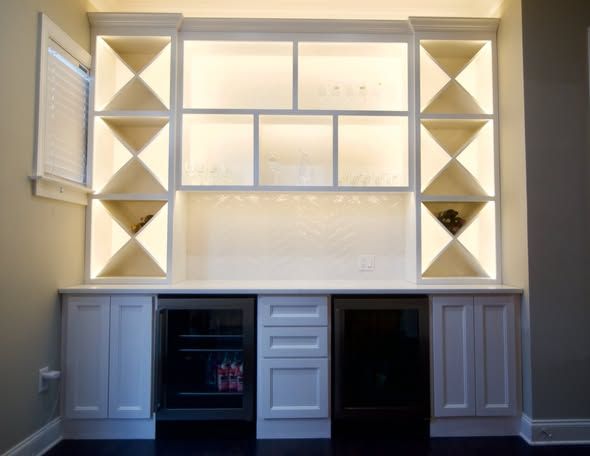 Built-in white shelving and cabinets with geometric cubbies and a glass-front display wall