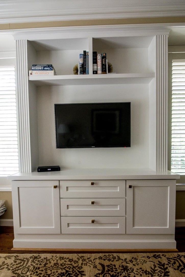 Built-in white entertainment center with a wall-mounted TV and shelves in a bright living room