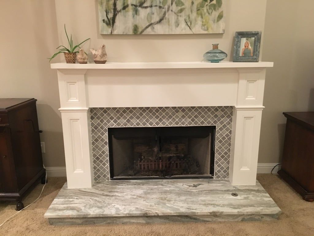 Living room fireplace with white mantel, gray tile surround, and decorative items on top