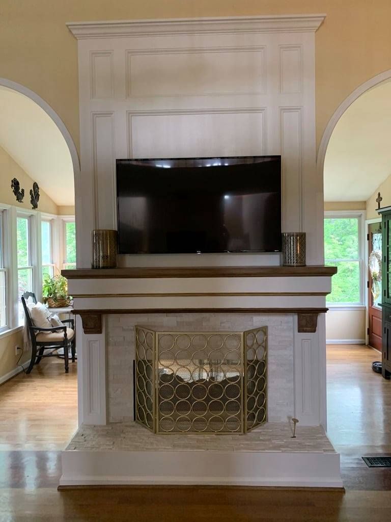 Elegant white fireplace with a large flat-screen TV mounted above it in a bright living room.