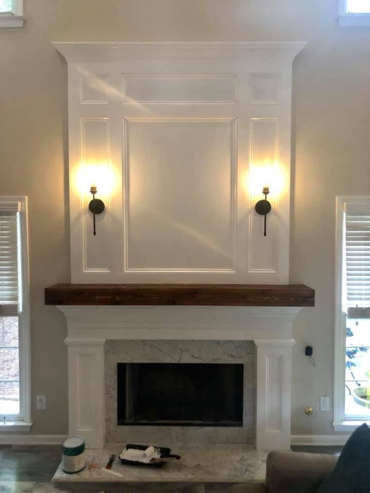 White fireplace with dark mantel and two wall sconces in a bright living room.