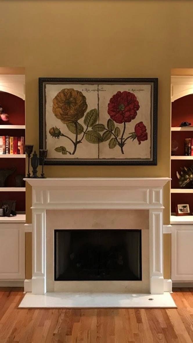 Elegant living room fireplace with white mantel and framed floral artwork above it