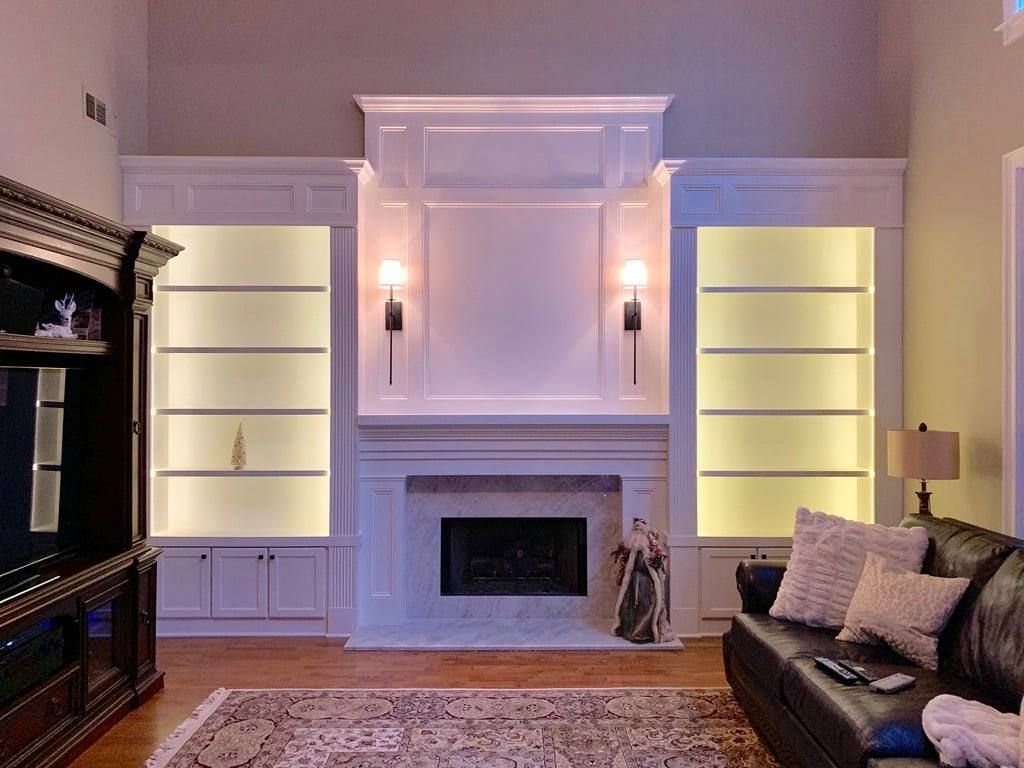Elegant living room with built-in shelves, fireplace, and a dark sofa in warm lighting