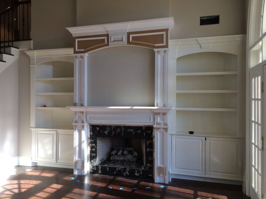 Built-in white bookshelves and fireplace with mantel in a bright living room