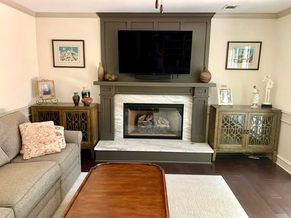 Living room with fireplace, wall-mounted TV, beige sofa, and wooden coffee table.