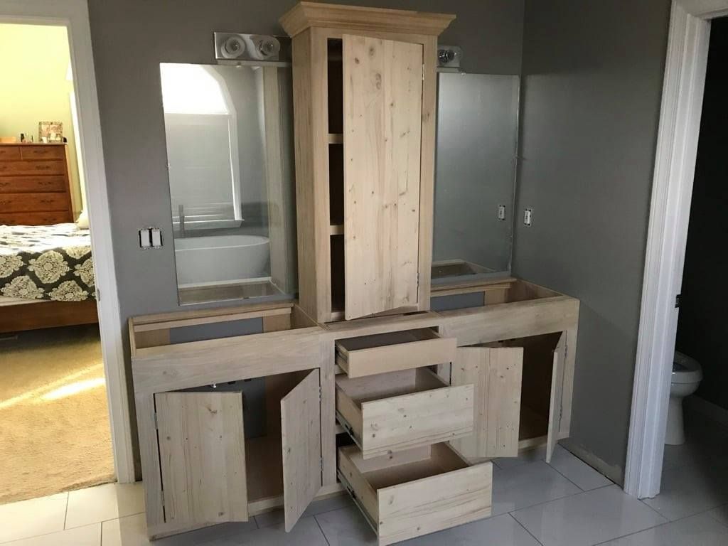 Wooden dresser with mirror, open drawers, and cabinet in a bedroom against gray walls