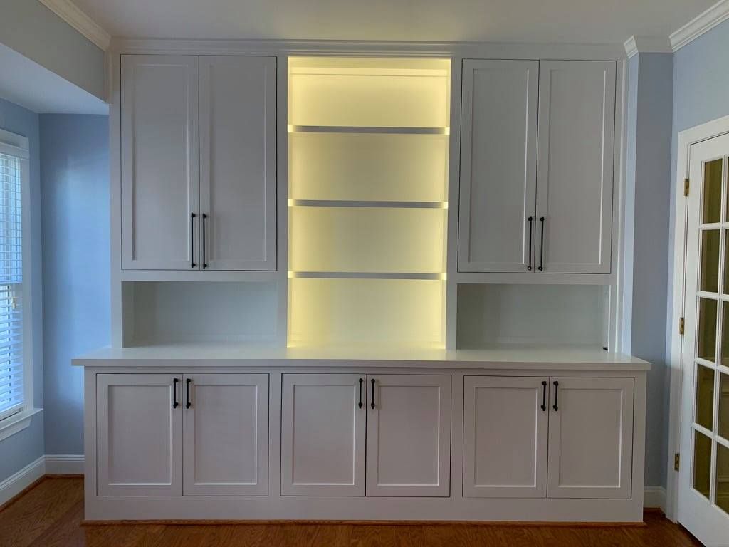 Built-in white cabinets with lit central shelves in a bright room.