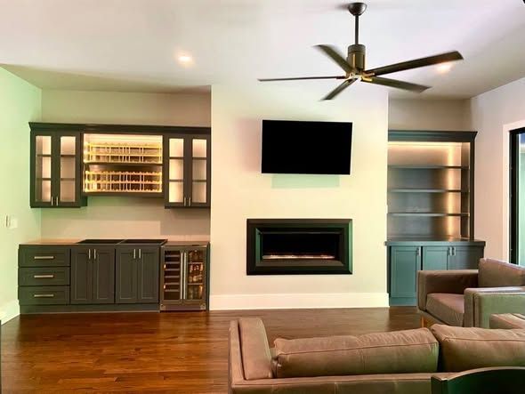 Modern living room with wall-mounted TV, fireplace, built-in cabinets, and hardwood floors