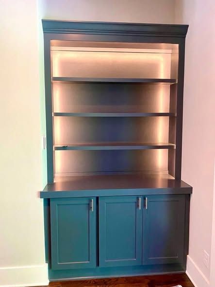 Dark wood hutch with open shelves and teal cabinet doors against a light wall.