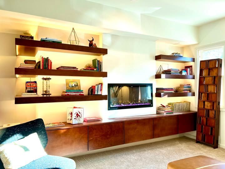 Modern living room with wall-mounted TV, wooden shelves, and warm lighting