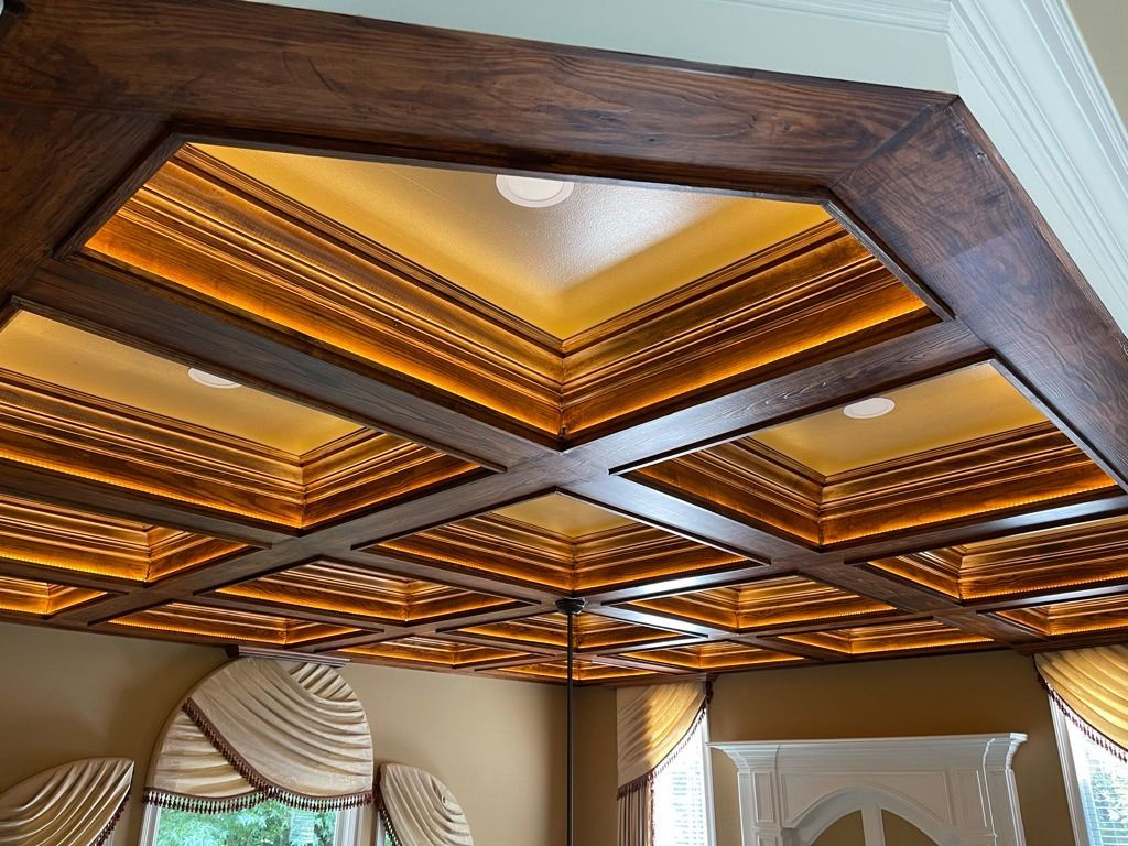 Ornate wood-paneled ceiling with amber lighting and geometric trim in a formal interior