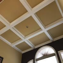 Tray ceiling with cream and white coffered panels above arched windows in a room
