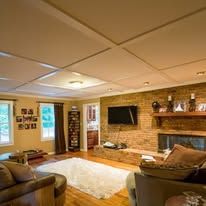 Cozy living room with brick fireplace, wall-mounted TV, couch, and soft white rug