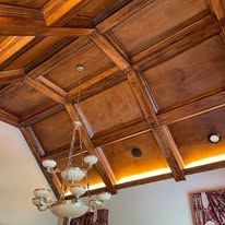 Wood-paneled coffered ceiling with a hanging chandelier and recessed lights in a room