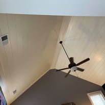 Ceiling with a black fan, beige walls, and a window in the corner.