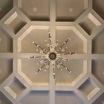 Ceiling with geometric recessed panels and a central starburst chandelier