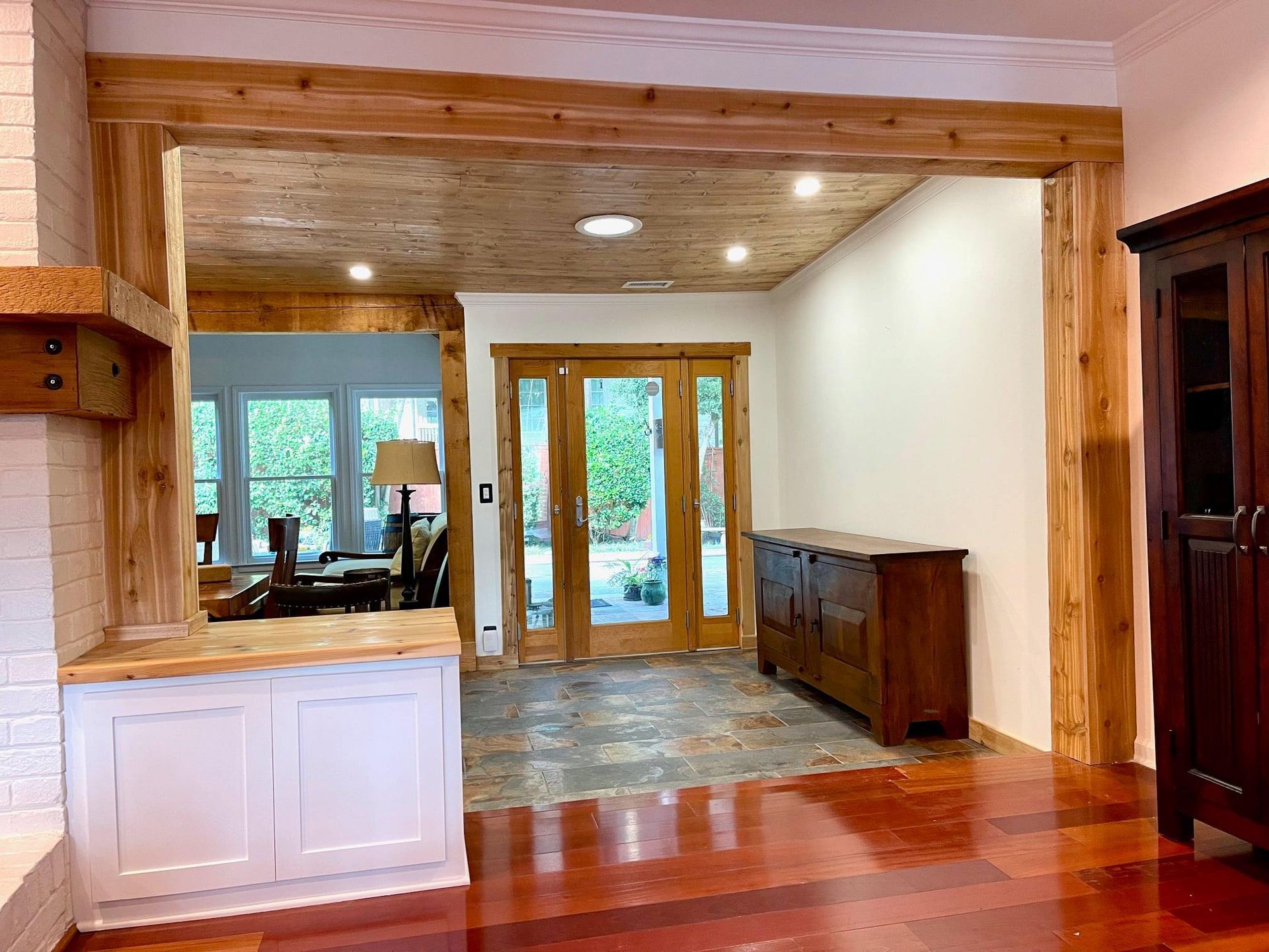 Open doorway to a tiled room with glass French doors, wood trim, white walls, and built-in cabinets