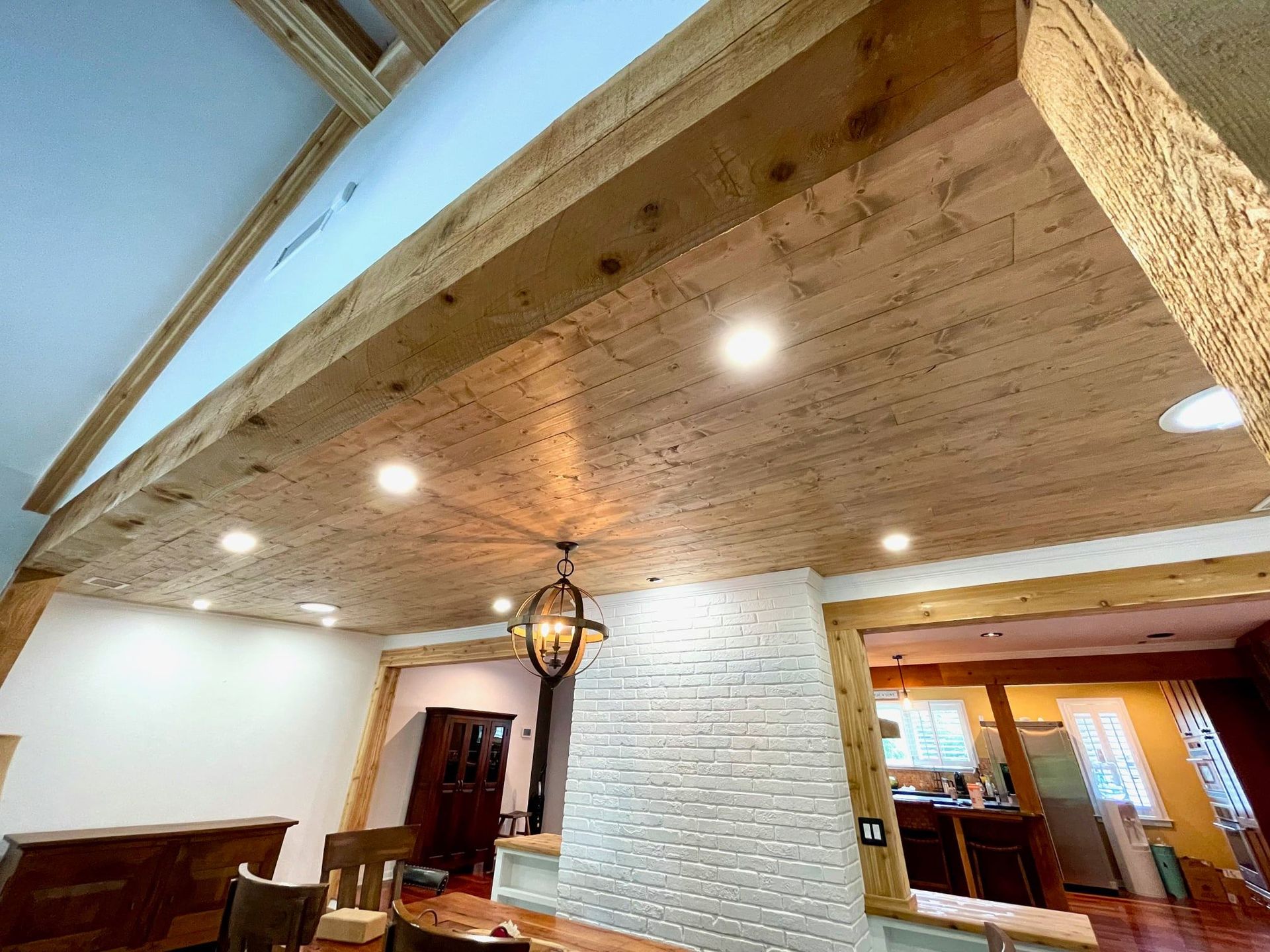 Wood-paneled vaulted ceiling with recessed lights in a rustic indoor room, seen from below