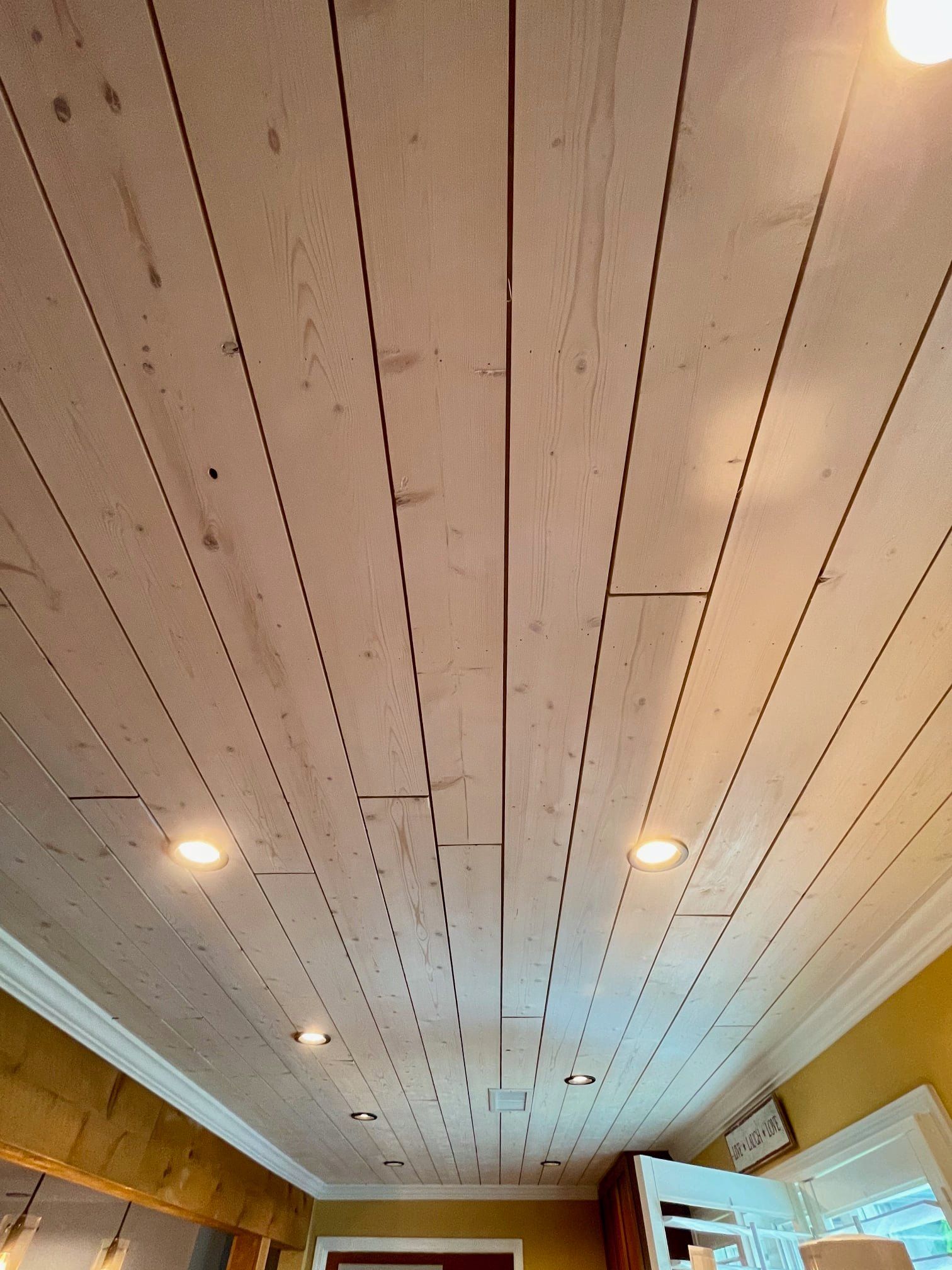 White paneled ceiling with recessed lights in a cozy room, viewed from below