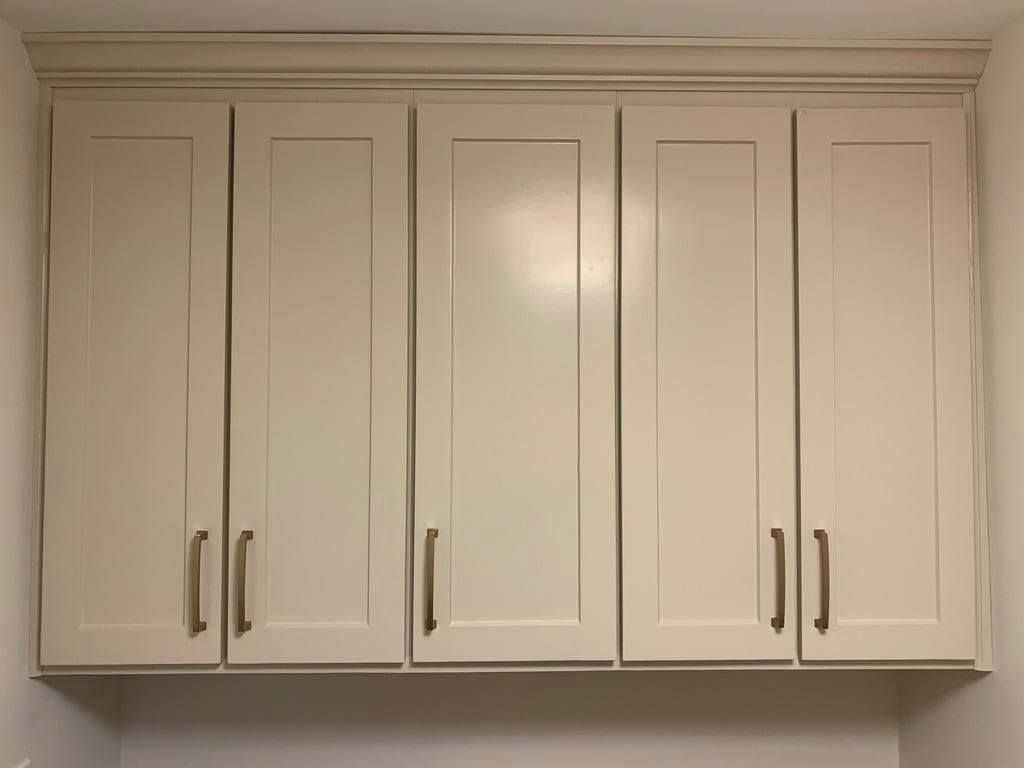 White kitchen wall cabinets with silver handles mounted above a countertop